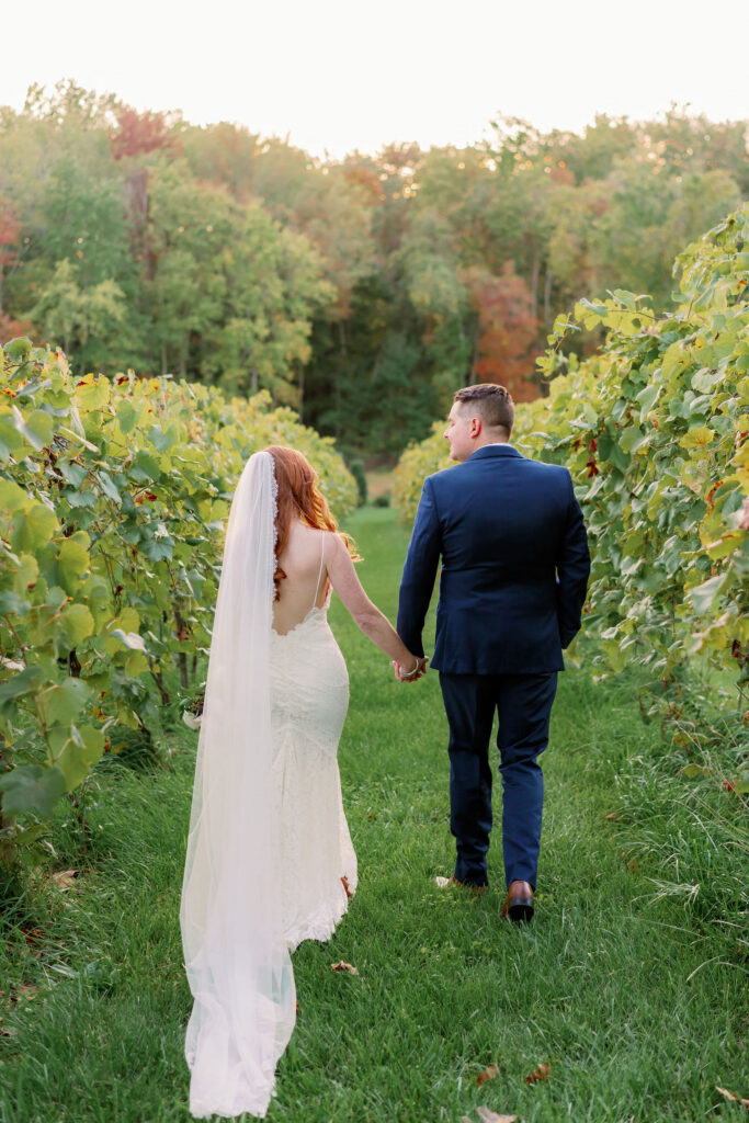 Bride and groom walking through a vineyard